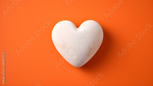 Top View of a White Stone Heart on a orange Background. Romantic Template with Copy Space