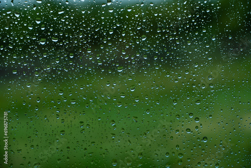 Drops of water flow down the surface of the clear glass on a black background. Texture for creativity.