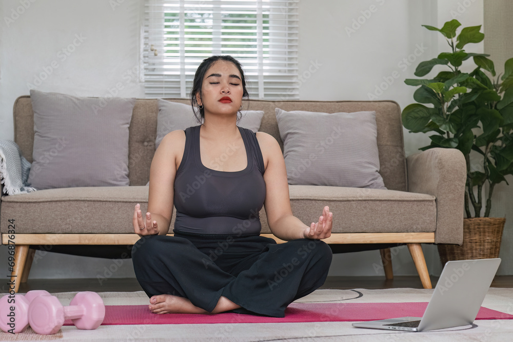 Overweight Asian woman exercising at home on a fitness mat. Beautiful Caucasian woman in casual clothes Preparing to do yoga Practice exercise in the living room
