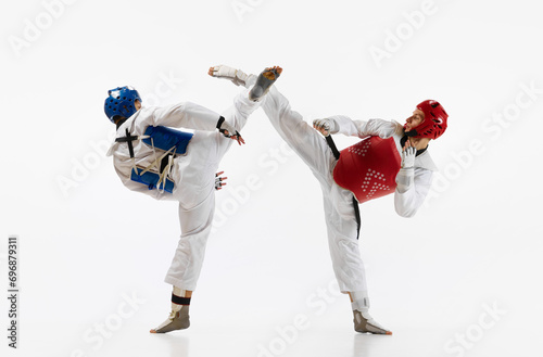 Athletic, strong young men, taekwondo athletes in motion, fighting, training isolated over white background. Concept of martial arts, combat sport, competition, action, strength, education