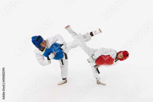 Athletic, motivated young men, taekwondo athletes in motion, practicing, training isolated over white background. Concept of martial arts, combat sport, competition, action, strength, education