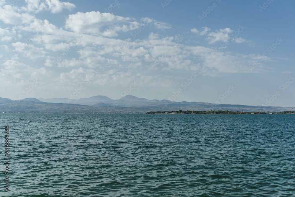 view of sevan huge blue lake shore with mountain peaks far ahead windy with waves