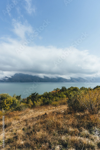 amazing beautiful top view of blue sevan lake in armenia with autumn trees below and vegetation with fluffy white clouds around photo