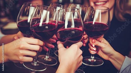 Celebration. A group of friends with glasses of red wine celebrating a birthday or other important event. Party with expensive wine from French grape varieties. Hands close-up.