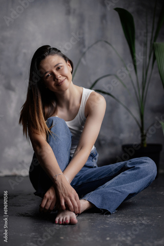 Portrait of an attractive girl with a charming smile. A girl of oriental appearance sits on the floor in a stylish apartment. Lifestyle