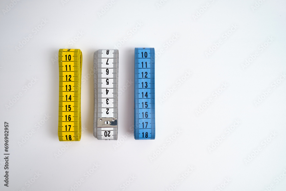 Multi-colored measuring tapes on a light background. Tool for measuring length and volume. Tape for measuring in sewing production or the volume of the human body Multi-colored measuring tapes on a light background. Tool for measuring length and volume. Tape for measuring in sewing production or the volume of the human body