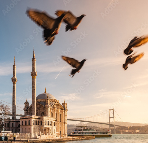 A wonderful sunset view of the Istanbul Bosphorus. A mosque on the Bosphorus. Birds flying at sunset. Ortakoy historical mosque, Büyük Mecidiye Mosque,  photo