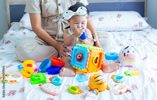 Mother and child playing with children's toys in the house,Mother and child are on the floor in the living room and play with her little child. The child likes to play very much. Around them are child