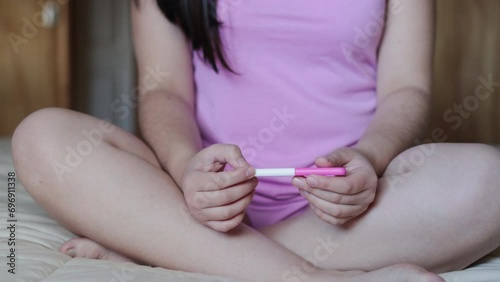 Wallpaper Mural Unrecognizable worried Young Woman, in a Pink Pajama seeing the Results of a Pregnancy Test on her Bed. Fertility issues Torontodigital.ca