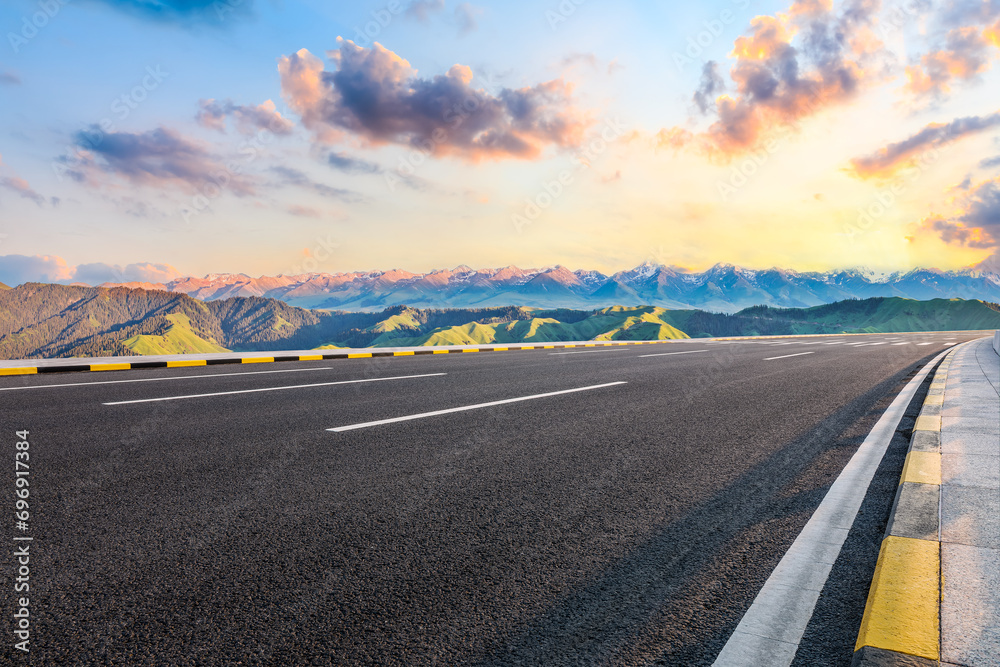 Fototapeta premium Asphalt highway road and green mountain with sky clouds at sunset