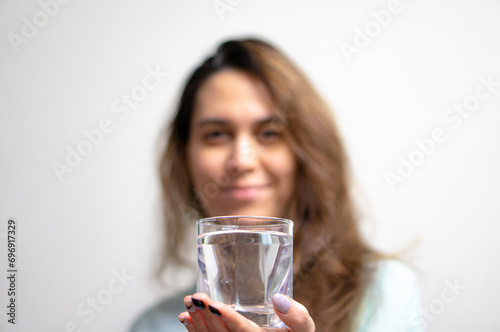 A glass of clean drinking water in your hand. There is a woman in the background.