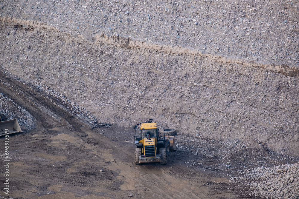 A large, deep crushed stone quarry with heavy equipment at the bottom A large, deep crushed stone quarry with heavy equipment at the bottom