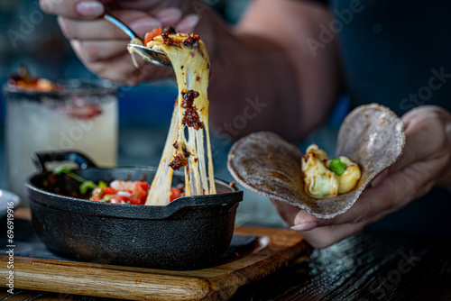 Queso Fundido. Oaxaca and chihuahua cheese on a skillet with chorizo and pico de gallo, served with blue corn tortillas
