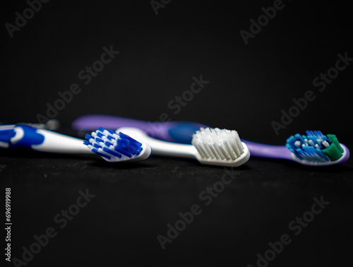 Three toothbrushes of different color on black background