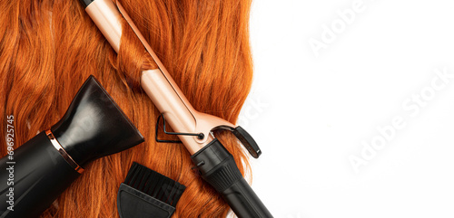 Long wavy red female hair, hair blow dryer, and Curling Iron on white isolated background. Hairdressing Products, coloring in bright colors