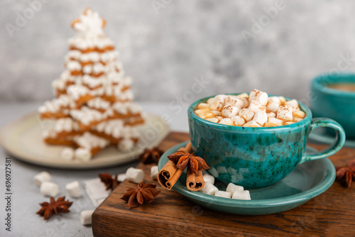 Hot drink with marshmallows and candy cane in blue cup on texture table.Cozy seasonal holidays.Hot cocoa with gingerbread Christmas cookies.Hot chocolate with marshmallow and spices.Copy space.