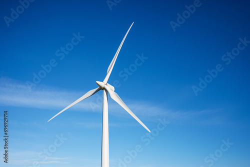 Close up of single wind mill turbine in front of blue sky