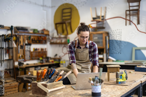 Young craftswoman using laptop in her workshop
 photo