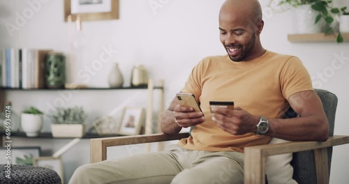 Man, phone and credit card on sofa with banking for online shopping, fintech and internet payment in living room. Black person, smartphone and happy for web transaction or discount on sale website photo