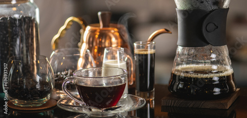 Fototapeta Naklejka Na Ścianę i Meble -  drip coffee, Barista making drip coffee by pouring spills hot water on coffee ground with prepare filter from copper pot to glass transparent chrome drip maker on wooden table in cafe shop