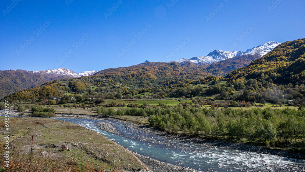A serene mountain landscape featuring a meandering river with snow-capped peaks in the background, illustrating the concept of natural beauty or environmental conservation