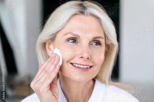 Mature woman applying hyaluronic moisturizing toner with cotton pads