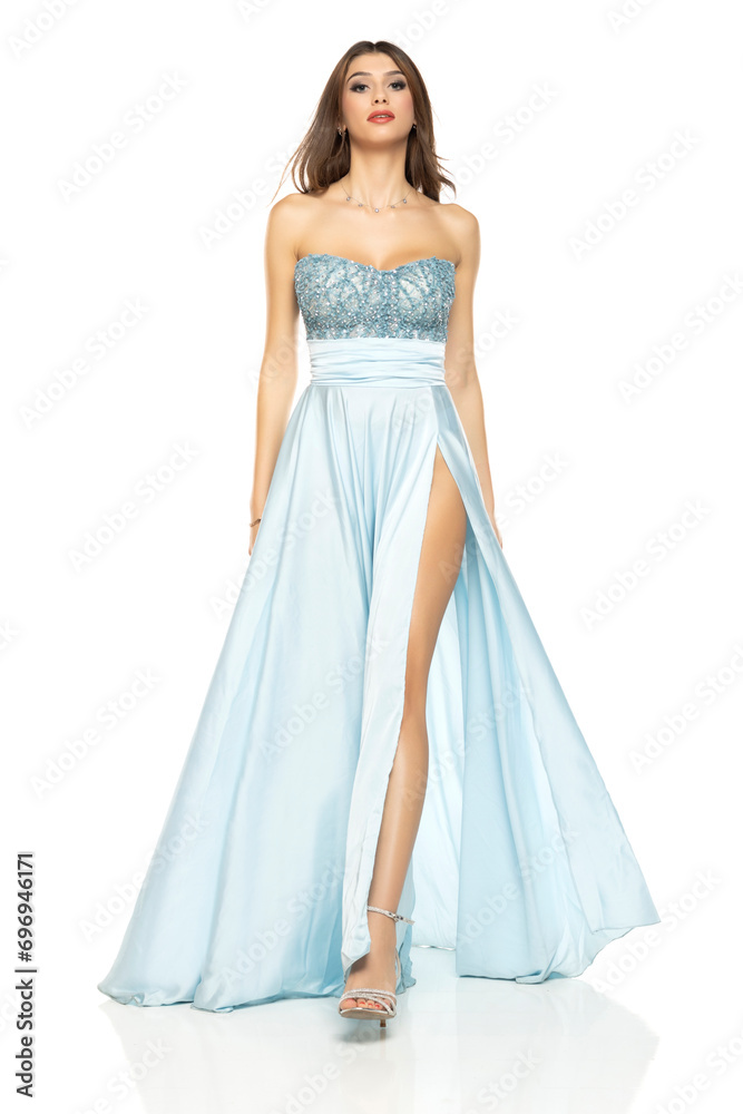 Full length of gorgeous elegant sensual brunette woman walking in blue evening dress isolated on white studio background Full length of gorgeous elegant sensual brunette woman walking in blue evening dress isolated on white studio background