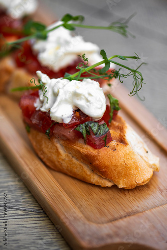 Bruschetta with tomatoes, feta cheese and herbs on wooden board . mozzarella and arugula. Canape
