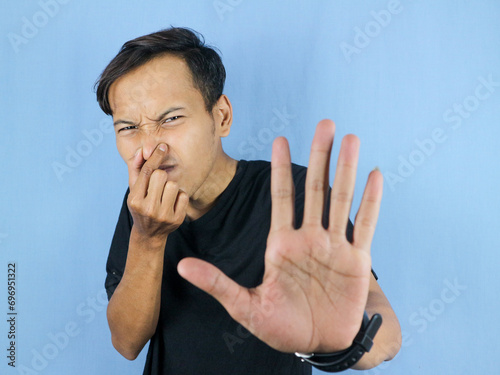 gesture handsome Asian man smelling something stinky and disgusting, intolerable smell photo