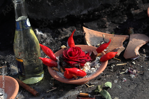 Macumba offering consisting of a rose amidst red peppers on a broken ceramic plate photo