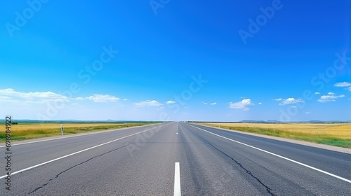 highway in the grassland background of blue sky and bright clouds, long road stretches into the distance. empty street on a beautiful sunny day © @_ greta
