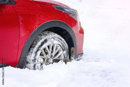 Wheel stuck in snow, snowfall in the city. Snow covered car wheel, close up.