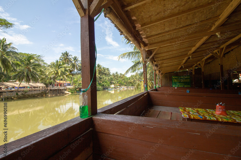 A tranquil riverside view from a wooden hut with seating arrangements