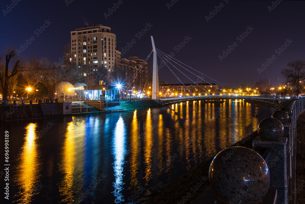 Fototapeta premium Scenic view of the Kharkiv river with a pedestrian bridge and embankment in the city on an autumn evening
