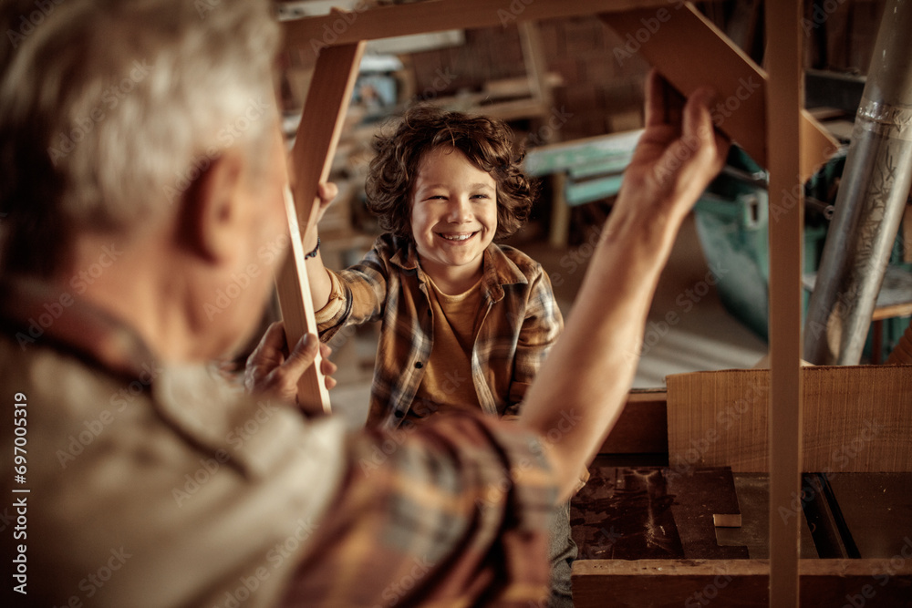 Little grandson having fun with grandfather in a carpentry shop Little grandson having fun with grandfather in a carpentry shop