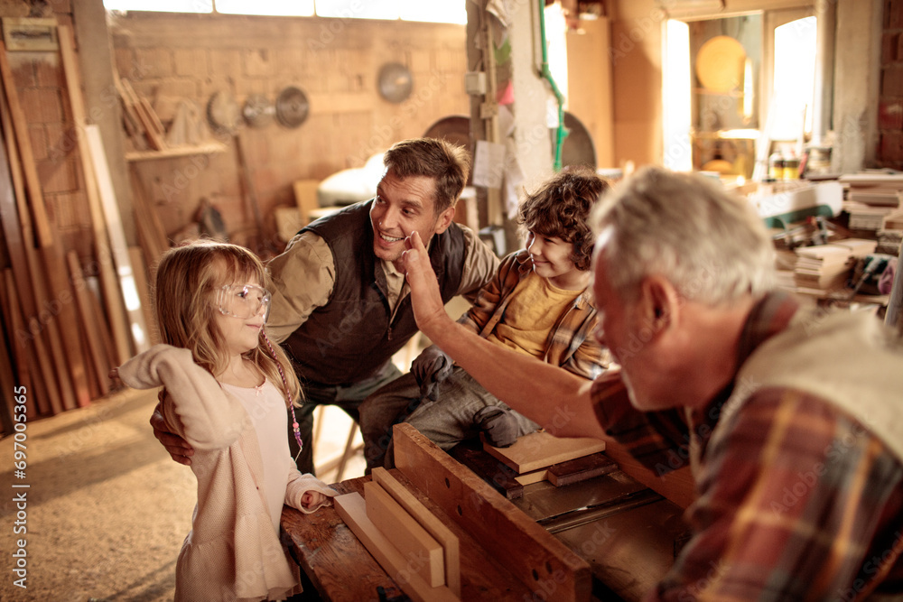 Father and children with grandfather in a woodworking workshop Father and children with grandfather in a woodworking workshop
