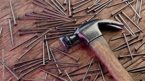 Old stained iron hammer on wooden table surrounded with nails. 3D illustration