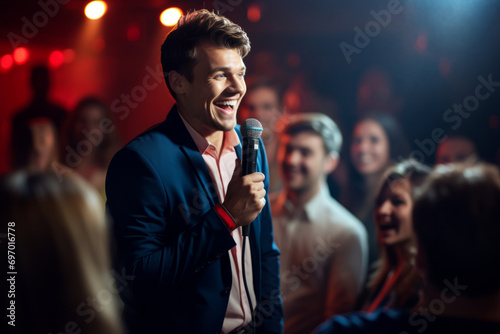 Handsome male stand-up comedian holding a microphone in front on cheerful audience. Man in a spotlight talking to a crowd.