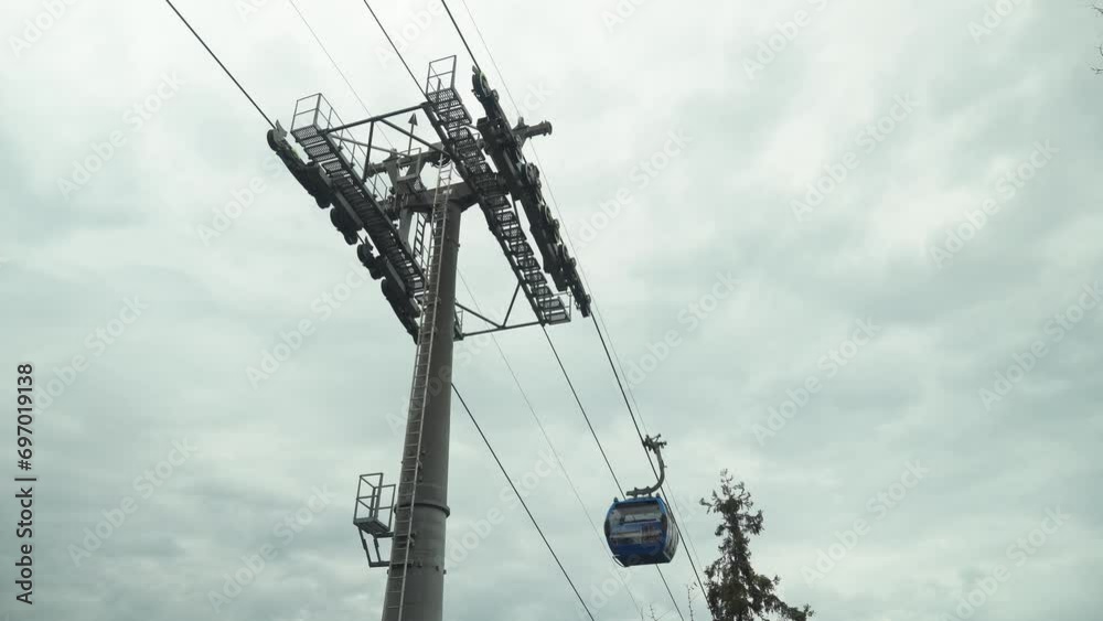 Funicular cable car cabin moves to destination, reaching the required point with ease. Recreational touristic experience against the overcast background. Tourist transportation on vacation