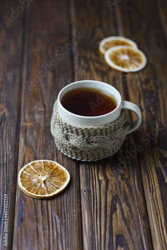 A light ceramic tea mug with dried orange slices on a wooden table. Selective accent.