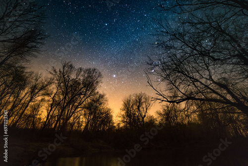 The starry sky and Milky Way above open fields and trees