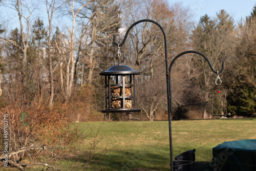 This beautiful bird feeder hangs from a post to help keep wildlife well fed. The black bars act as a cage to keep larger critters from taking too much. This hangs from a black shepherds hook.