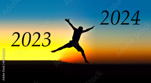 A man jumps from 2023 to 2024 against the backdrop of sunset. New Year 2024