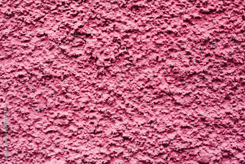 Home facade texture. Red rough surface. Grunge grain. Crushed rocks in the wall. Exterior home decoration. Stucco wall pattern. Pink color retro design. Noisy design background.