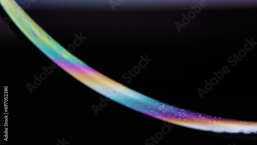 Colorful soap bubble disappearing into the dark. Abstract macro background. 
