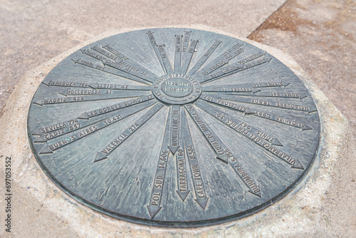 a metallic circle indicating the direction and distance to different locations in the world from the park of Sant Eloi in Tarrega, Province of Lleida, Catalonia, Spain photo