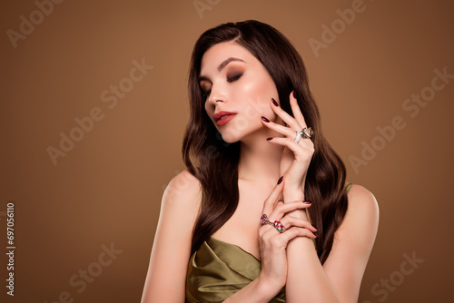 Photo of sweet dreamy lady wear silk dress showing jewelry touching cheek empty space isolated brown color background