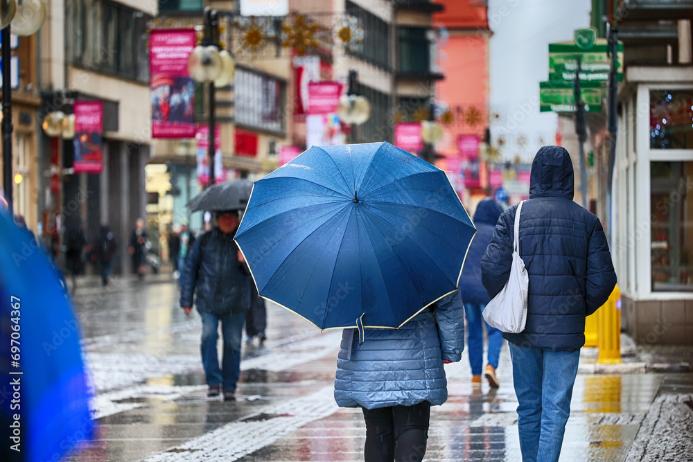 Ludzie pod parasolem w czasie deszczu i wiatru.  - obrazy, fototapety, plakaty 