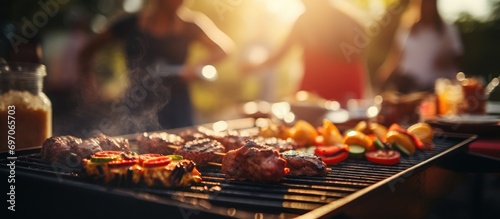 A group of people are having a party outdoors. Focus on the meat being grilled
