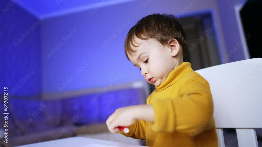 Focused little kid wearing yellow sweater dealing with felt pen. Baby boy getting ready to start drawing. Focused little kid wearing yellow sweater dealing with felt pen. Baby boy getting ready to start drawing.